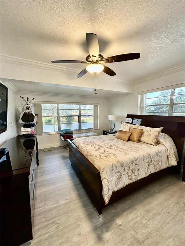 bedroom featuring hardwood / wood-style floors, ceiling fan, a textured ceiling, and ornamental molding