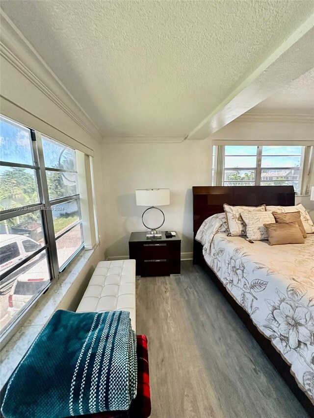 bedroom featuring hardwood / wood-style floors, crown molding, and a textured ceiling