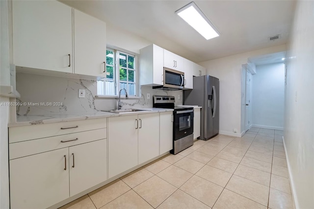 kitchen featuring light tile patterned floors, backsplash, appliances with stainless steel finishes, sink, and white cabinetry