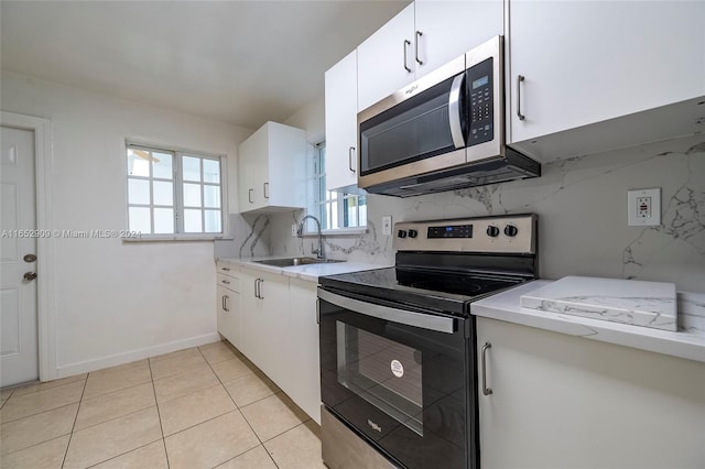 kitchen featuring light tile patterned floors, stainless steel appliances, sink, decorative backsplash, and white cabinetry