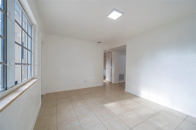 spare room with a wealth of natural light and light tile patterned flooring