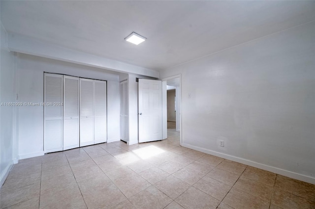 unfurnished bedroom with two closets and light tile patterned flooring