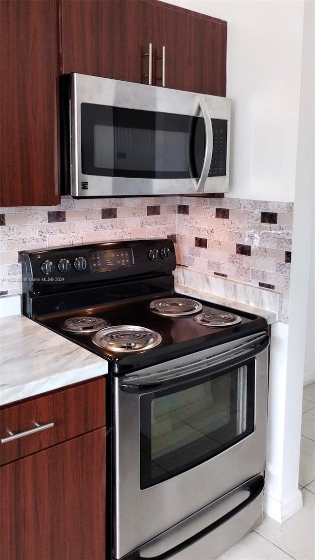 kitchen with light tile patterned floors, stainless steel appliances, and decorative backsplash