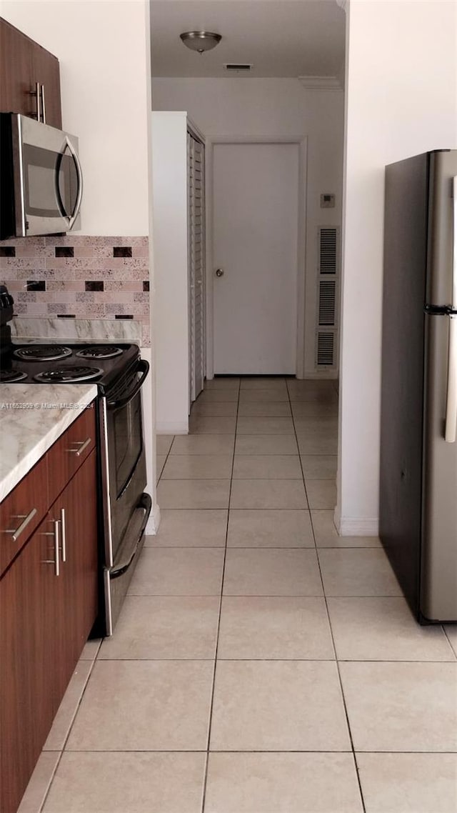 kitchen with appliances with stainless steel finishes, decorative backsplash, and light tile patterned flooring