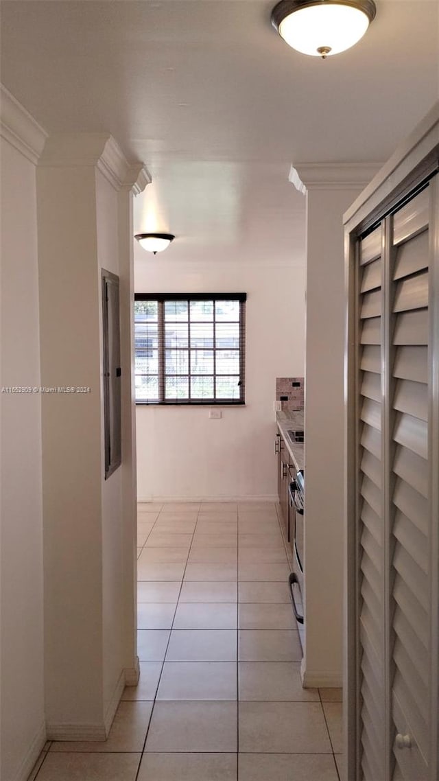 corridor with ornamental molding and light tile patterned flooring