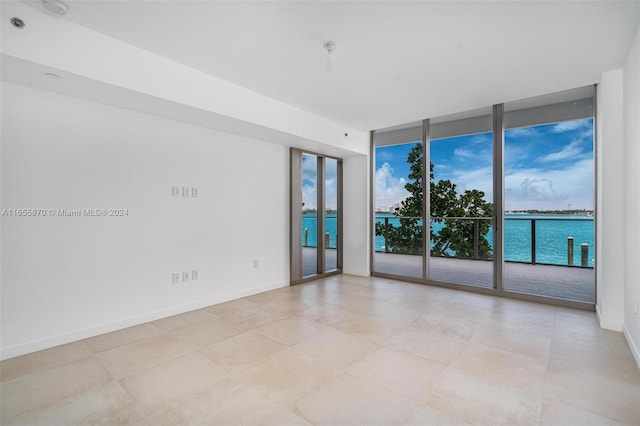 unfurnished room featuring a water view, floor to ceiling windows, and a healthy amount of sunlight