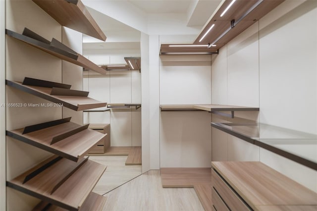 walk in closet with light hardwood / wood-style floors