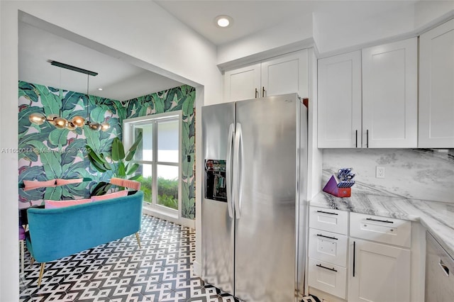 kitchen featuring white cabinetry, pendant lighting, light stone countertops, and stainless steel refrigerator with ice dispenser