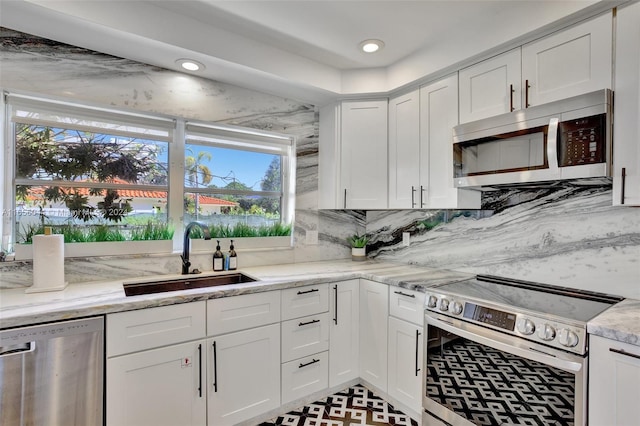 kitchen featuring appliances with stainless steel finishes, white cabinetry, sink, and tasteful backsplash