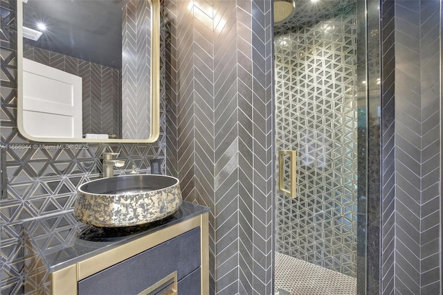 bathroom featuring vanity, a tile shower, backsplash, and tile walls