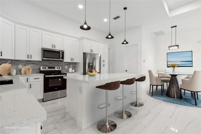 kitchen with appliances with stainless steel finishes, pendant lighting, and white cabinets