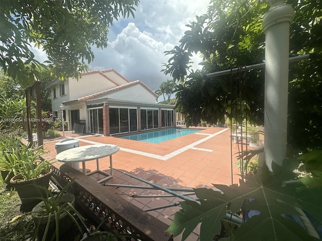 view of swimming pool featuring a sunroom and a patio