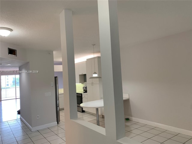 kitchen with a textured ceiling, light tile patterned flooring, stainless steel appliances, and white cabinets