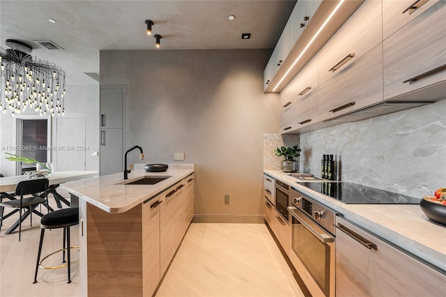 kitchen with sink, oven, a kitchen bar, black electric cooktop, and light wood-type flooring