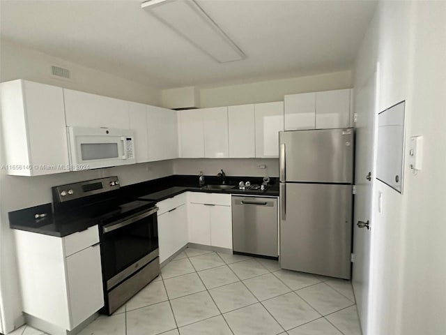 kitchen with light tile patterned floors, white cabinetry, and stainless steel appliances