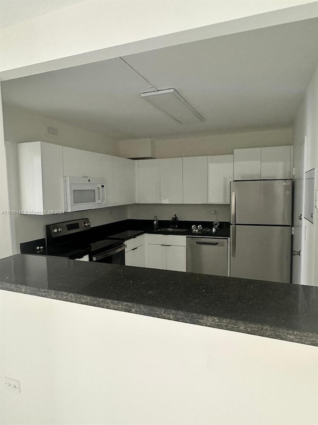 kitchen featuring appliances with stainless steel finishes, white cabinetry, and sink