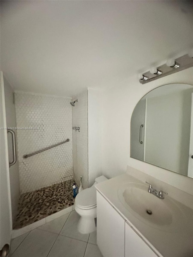 bathroom with tile patterned flooring, walk in shower, toilet, and vanity