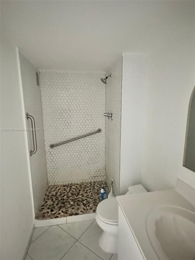 bathroom with vanity, toilet, tiled shower, and tile patterned flooring