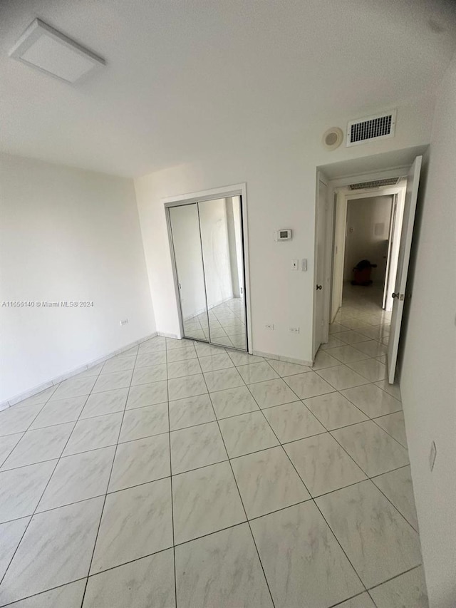 interior space featuring a textured ceiling, a closet, and light tile patterned floors