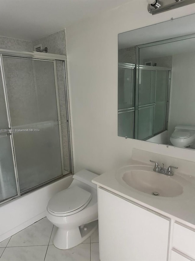 full bathroom featuring tile patterned flooring, toilet, bath / shower combo with glass door, and vanity