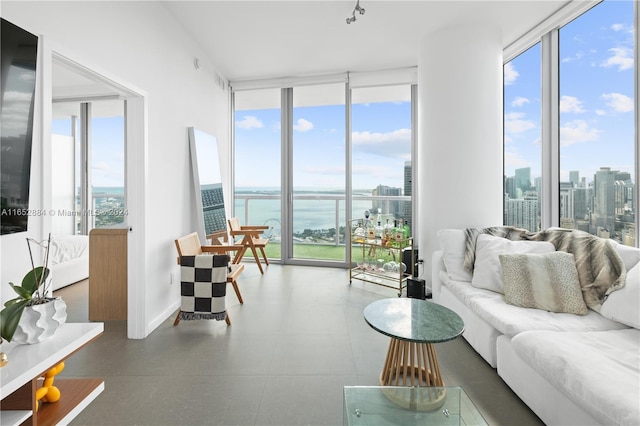 living room featuring a wall of windows, a water view, and a city view