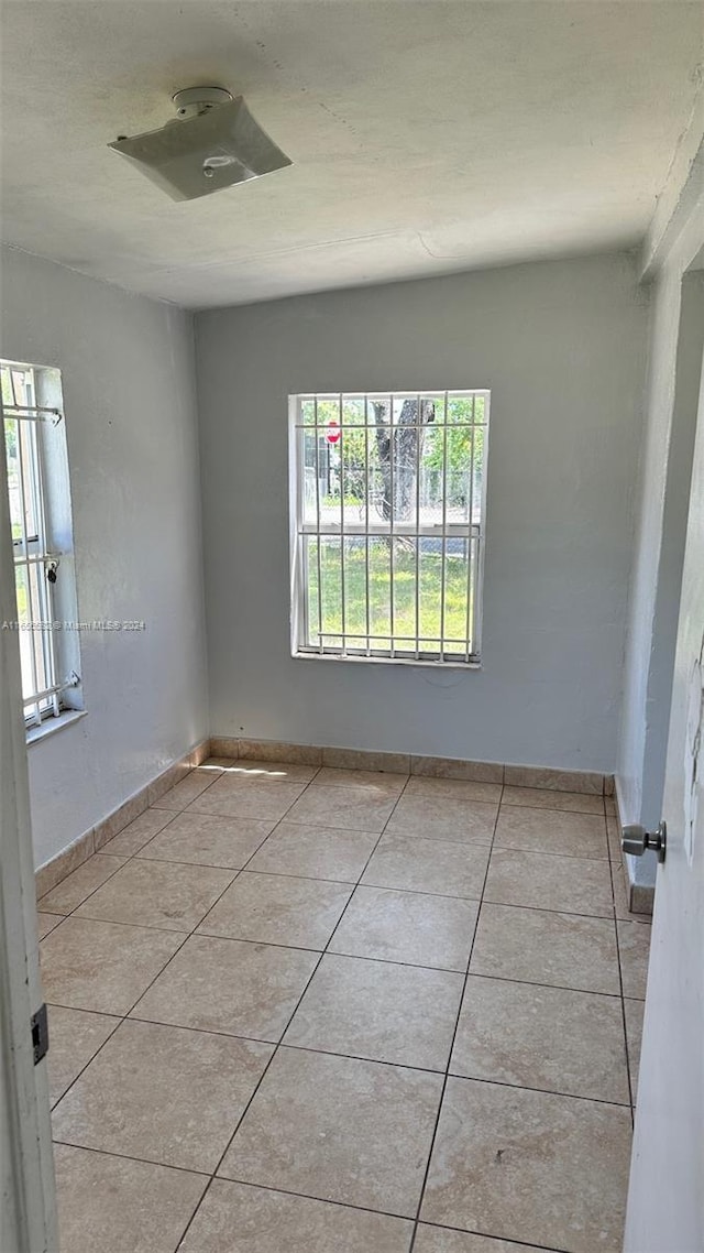 tiled spare room featuring baseboards