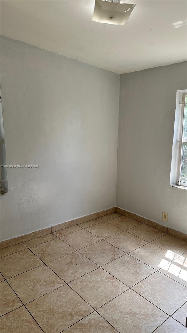 spare room with tile patterned floors and baseboards