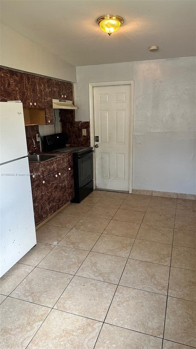 kitchen with black electric range, white fridge, light tile patterned floors, and tasteful backsplash