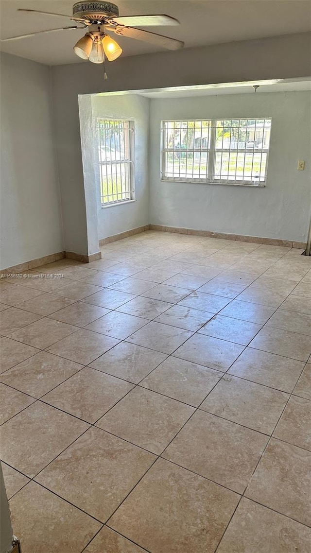 spare room with ceiling fan, light tile patterned floors, and plenty of natural light