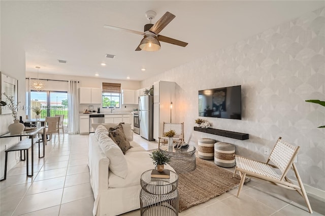 living room with light tile patterned floors, sink, and ceiling fan with notable chandelier