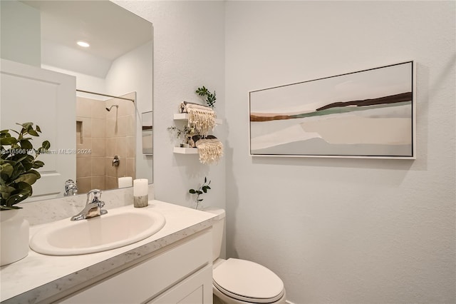 bathroom with vanity, toilet, and a tile shower