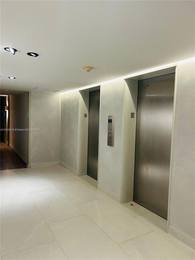 hallway with elevator and light tile patterned flooring