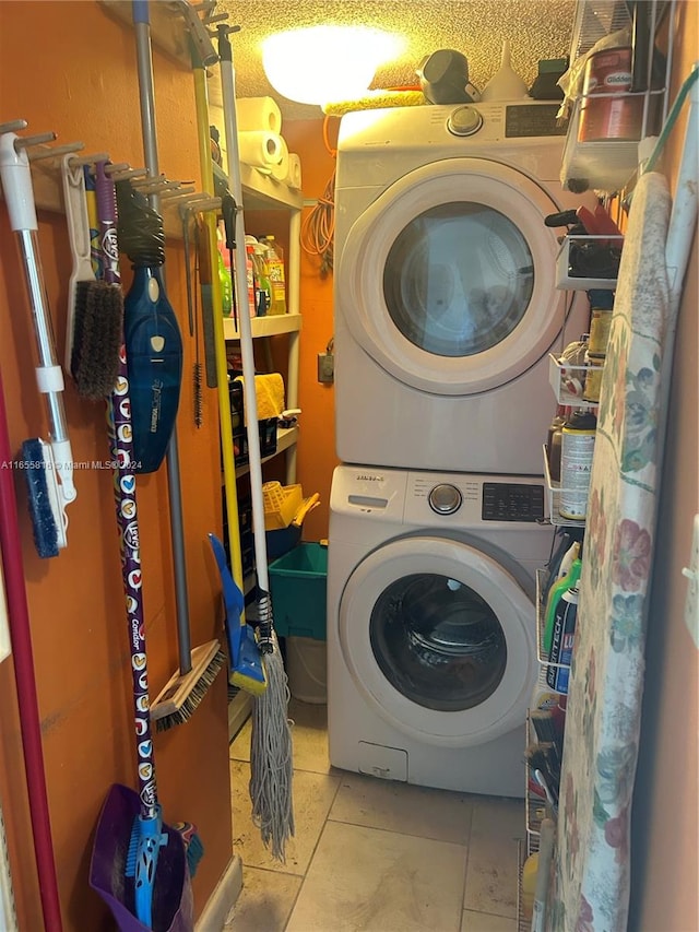 laundry area featuring stacked washer / drying machine and light tile patterned floors