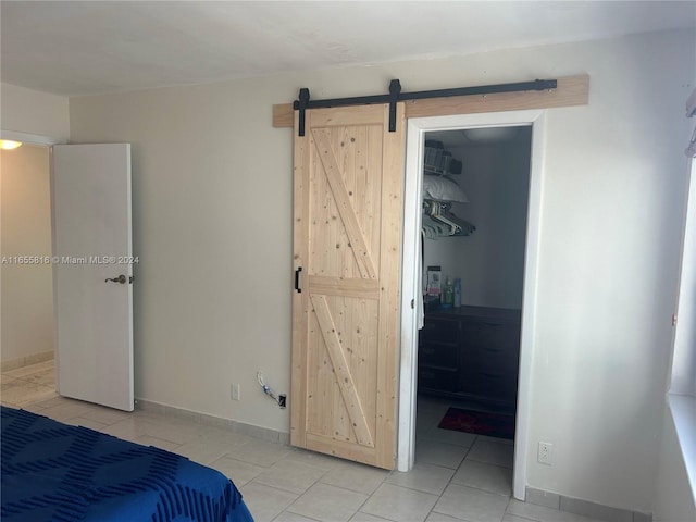 bedroom with light tile patterned flooring, a closet, a barn door, and a walk in closet