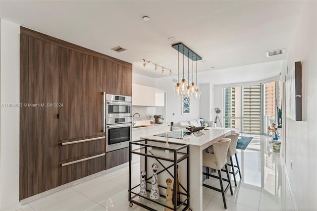 kitchen featuring a kitchen island with sink, pendant lighting, light tile patterned flooring, and a kitchen breakfast bar