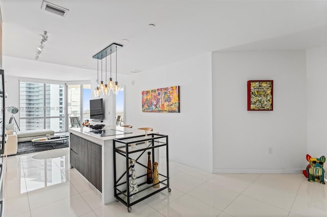 kitchen with light tile patterned floors, light stone counters, a notable chandelier, track lighting, and pendant lighting