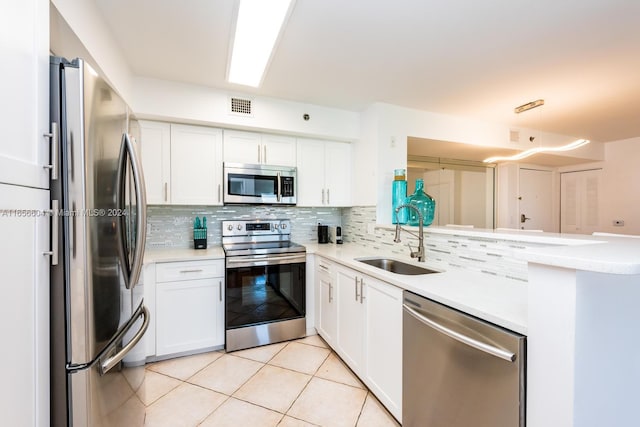 kitchen featuring appliances with stainless steel finishes, tasteful backsplash, white cabinetry, and sink