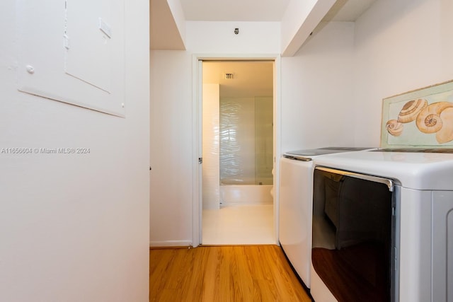 washroom featuring washing machine and clothes dryer and light hardwood / wood-style flooring