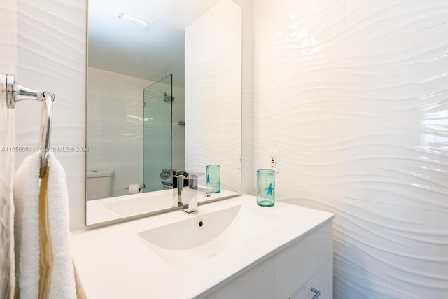 bathroom with vanity, toilet, and a tile shower