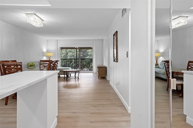 hall featuring light wood-type flooring and a textured ceiling