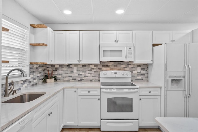 kitchen with white appliances, light stone countertops, sink, and white cabinets