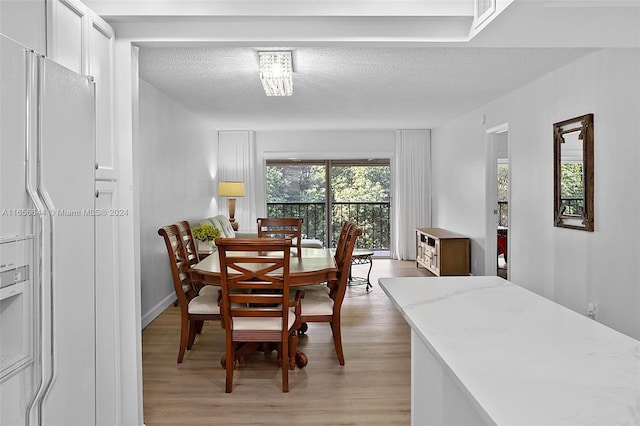 dining room with light wood-type flooring and a textured ceiling