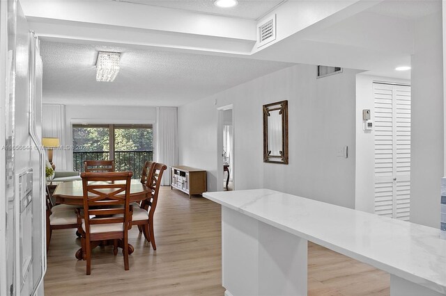 dining area featuring a textured ceiling and light hardwood / wood-style flooring