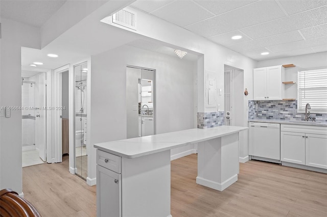 kitchen featuring white cabinets, white dishwasher, light wood-type flooring, sink, and decorative backsplash