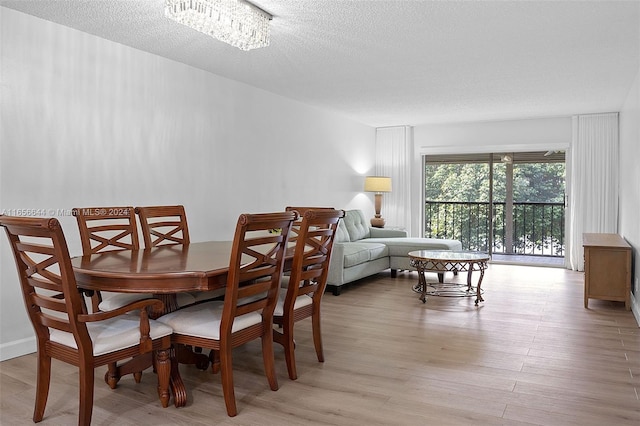 dining space with an inviting chandelier, light hardwood / wood-style floors, and a textured ceiling