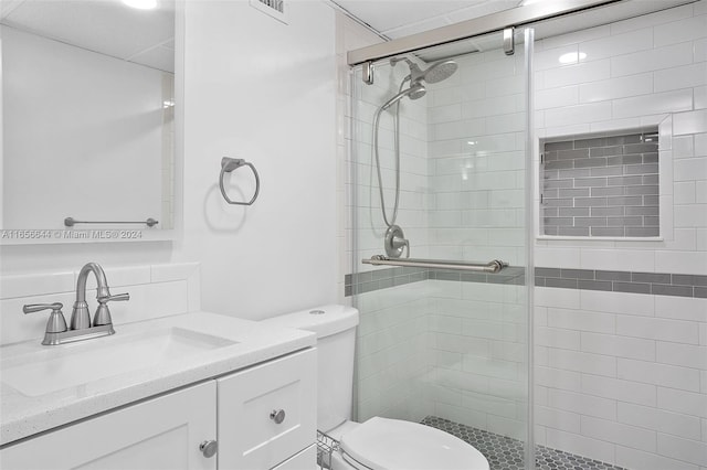 bathroom featuring a shower with door, vanity, and toilet