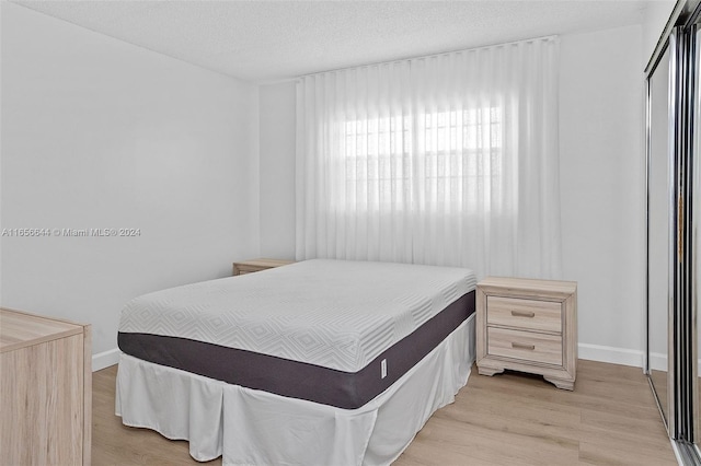 bedroom with a textured ceiling and light hardwood / wood-style flooring