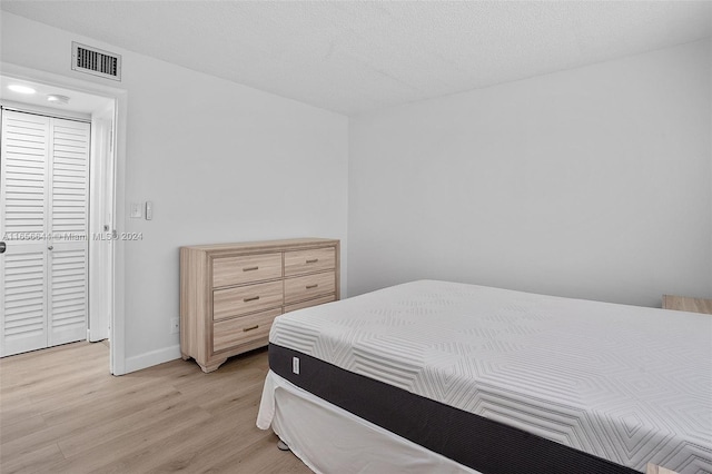 bedroom featuring a textured ceiling and light hardwood / wood-style floors