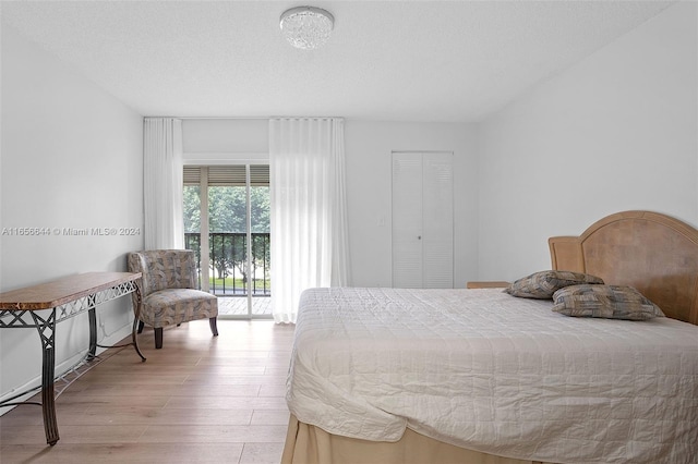 bedroom with light wood-type flooring, a textured ceiling, access to exterior, and a closet