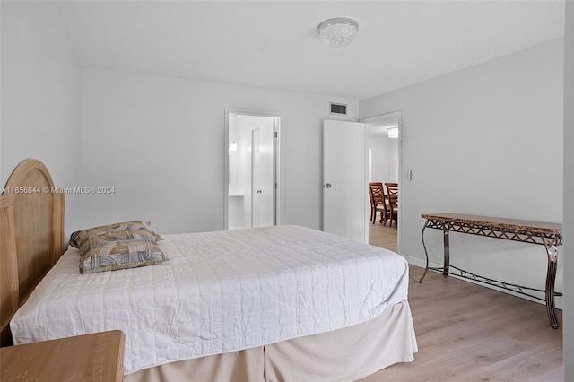 bedroom with light wood-type flooring and ensuite bath